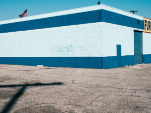 Minimal urban landscape photograph of architecture with the word sick spray painted on a blue building